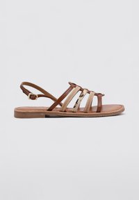 Sandalias de tiras en marrón y beige con suela plana, tiras texturizadas y cierre de hebilla en el talón.