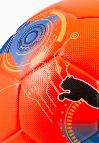 Balón de fútbol Puma con superficie texturizada de color naranja brillante y detalles gráficos en azul y negro, que incluyen una silueta de gato y diseños circulares.