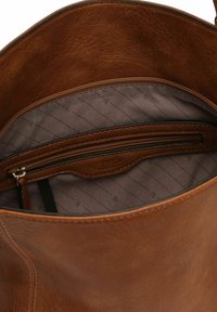 Innenraum einer braunen Lederhandtasche mit strukturierter Oberfläche, ausgestattet mit einer Reißverschlusstasche und einem bedruckten braunen Stofffutter.