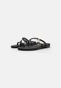 Svarta platta sandaler med tunna remmar, med en texturerad sula och metallisk bi-detalj på framfoten. Minimalistisk design och flexibel material.
