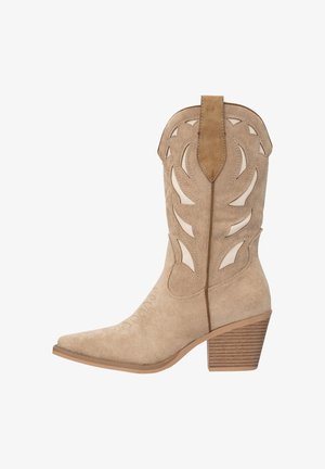 Beige suède cowboylaars met uitgewerkt bladmotief, spits toelopende neus en gestapelde hak. Gestructureerde zijkantdetails en contrasterende achterpaneel.
