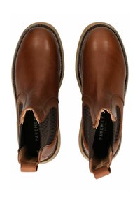 Bottes chelsea en cuir marron avec des panneaux élastiques sur les côtés, tissu noir texturé, bords cousus et une petite languette de tirage au niveau du talon.