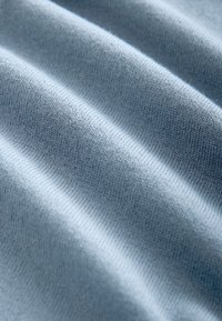 Tessuto blu chiaro con una texture liscia, caratterizzato da motivi a coste verticali e una morbida caduta. Ideale per applicazioni di abbigliamento e imbottitura.