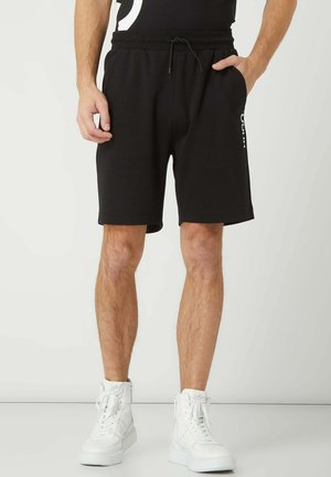 Shorts en coton noirs avec une taille élastique et un cordon de serrage. Comprend des poches latérales et un logo blanc le long de la cuisse gauche.