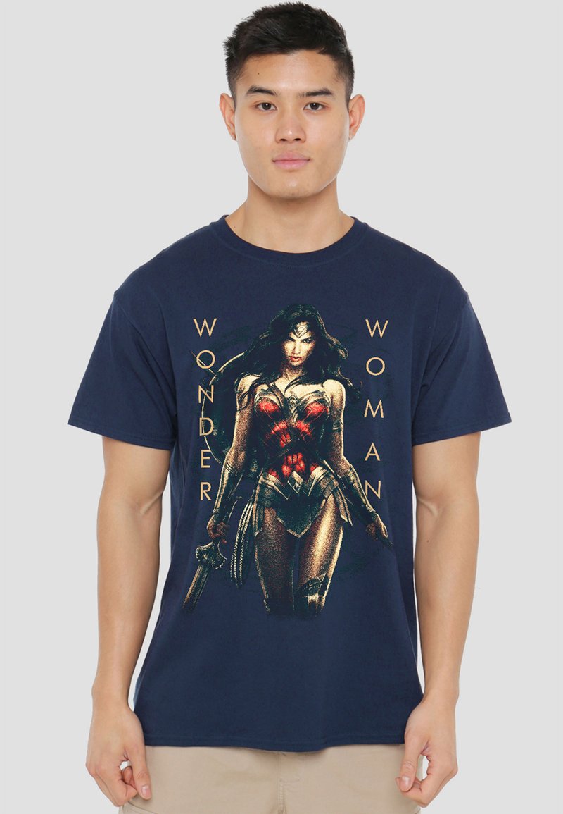 Man wearing navy blue t-shirt with graphic of Wonder Woman in armor holding sword, text "WONDER WOMAN" beside the figure.