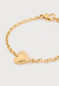 Βραχιόλι από χρυσό μέταλλο με ένα γοητευτικό καρδιά και μια κρυστάλλινη λεπτομέρεια. Η αλυσίδα αποτελείται από ενωμένους οβάλ κρίκους με κούμπωμα κλειδώματος.