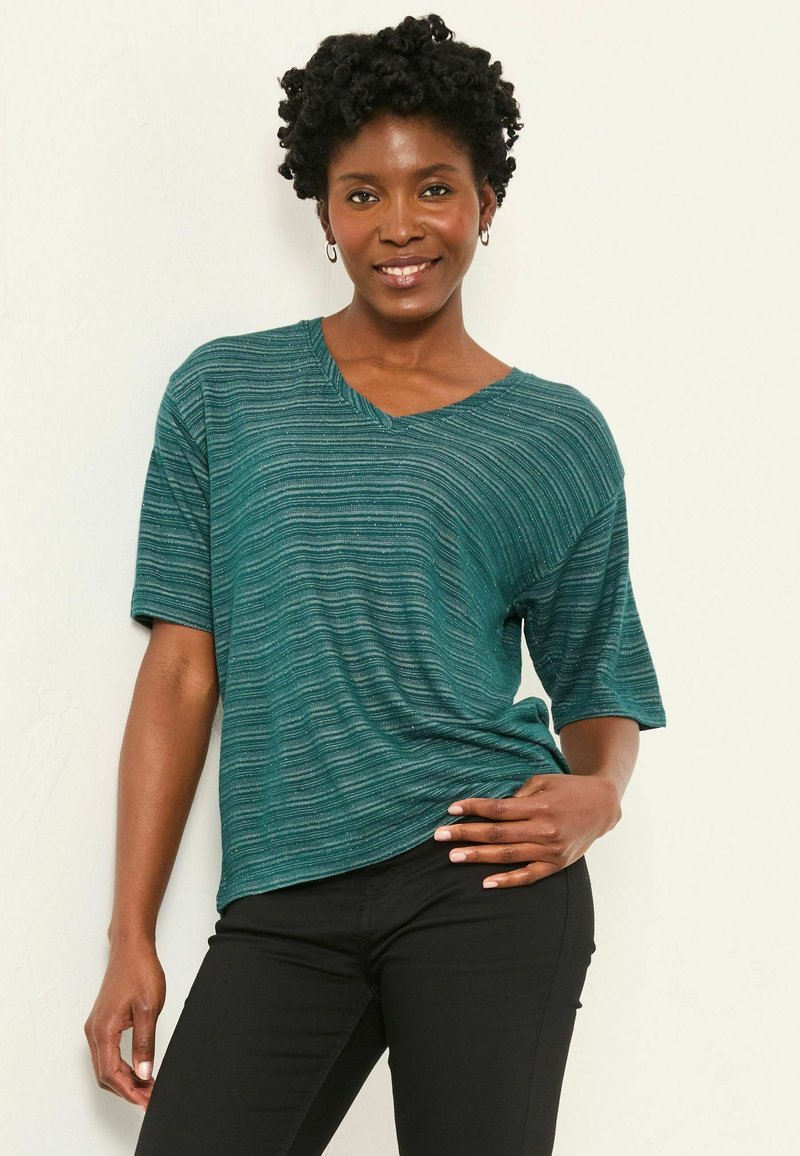 Turquoise v-neck top with short sleeves, featuring a textured stripe pattern. Paired with black fitted pants, creating a casual look.
