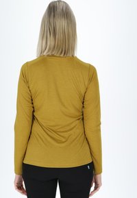 Langærmet, sennepsgul bluse med en glat tekstur og tætsiddende design. Har en rund halsudskæring og et lille mærke ved kanten.