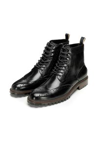 Botas de tobillo de cuero negro con diseño de punta de ala, cordones en la parte delantera, ojales de metal y suelas de goma texturizada. Presentan un lazo en el talón.