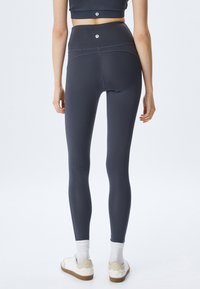 Højhævede marineblå leggings lavet af strækbart stof, med en glat tekstur, diskret logo på livet og tætsiddende silhuet.