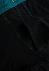 Meeste mustad aluspesu, millel on tekstuuriga türkiissinine vöökoht, kontrastsete õmblustega ja ühtlaselt sile tekstuur.