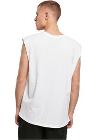 Weißes ärmelloses T-Shirt aus Baumwolle, mit Rundhalsausschnitt und lockerem Schnitt. Die Rückseite ist schlicht mit einem abgerundeten Saum.