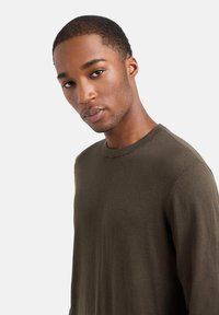 Maglione verde oliva a girocollo con finitura strutturata, caratterizzato da una vestibilità classica e polsini a coste discreti. Design semplice senza ulteriori motivi.