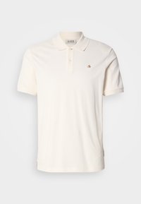 Πολιτεία με κοντά μανίκια σε μαλακό κρέμ βαμβάκι, με τριπλή κουμπότρυπα και μικρό κομμένο λογότυπο στο στήθος.