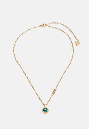 Gold chain necklace featuring a round emerald-colored gemstone pendant with a textured rim and a logo tag. Adjustable length for fit.
