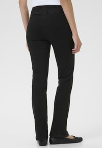 Schwarze Jeans mit schlankem Schnitt, ausgestattet mit einem mittelhohen Bund und leichtem Stretch für Komfort. Keine sichtbaren Metallteile oder Verzierungen.