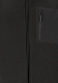 Sort zip-up jakke med struktureret stof, en enkelt lynlåslomme på brystet og et strømlinet design uden synlige mønstre.