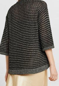 Svart- och vitrandig stickad topp med lös passform, trekvartslånga ärmar och rund halsringning, med ett strukturerat mönster och en mjuk finish.
