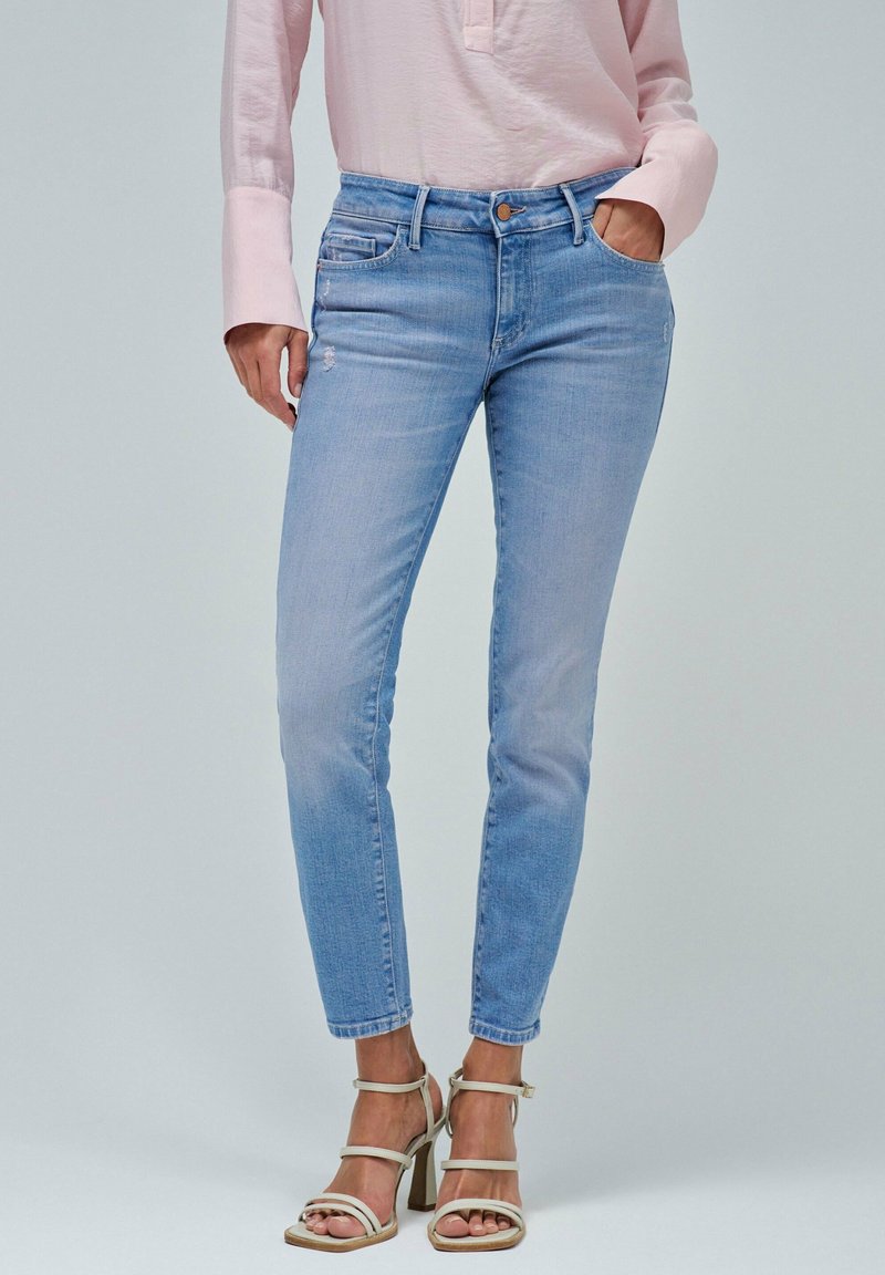 Jeans ajustados de color azul claro con cintura media, presillas para cinturón y bolsillos frontales, con un ligero desgaste en el muslo.