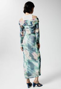 Šaty voľného strihu bez ramienok, ľahké, s kvetinovým vzorom v modrých a zelených odtieňoch; majú dlhé rukávy a priliehavý strih.