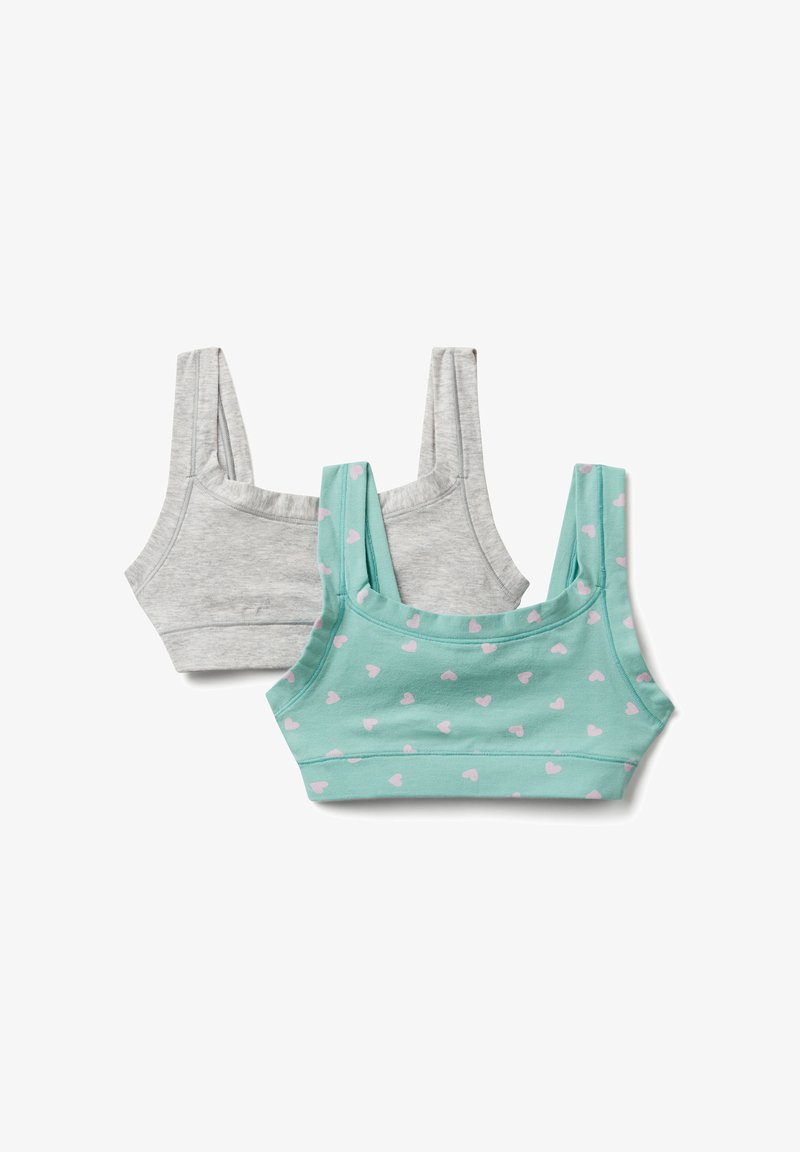Due bralette in cotone per ragazze, una grigia semplice e una turchese con cuori rosa, mostrate distese su uno sfondo bianco.