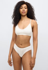 Σετ εσωρούχων σε κρεμ απόχρωση με υφασμάτινο σουτιέν με δαντελένιες πινελιές και ταιριαστό σλιπ ψηλόμεσο με ευαίσθητο μοτίβο.