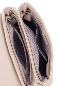 Světlobéžová kožená taška se dvěma zipovými přihrádkami. Interiér má růžový cikcakový vzor na tmavém pozadí. Hladký povrch.