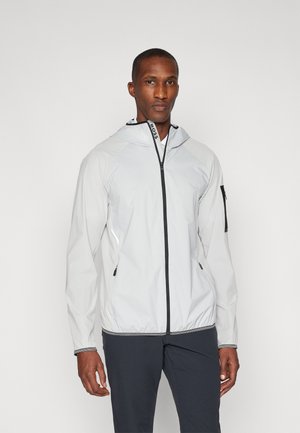 Veste à capuche gris clair avec une fermeture éclair frontale, des accents noirs et des poches zippées. Texture lisse, tissu léger et poignets élastiques.