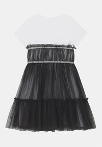 Abito in tulle nero con top bianco, caratterizzato da una vita arricciata con un nastro nero e la scritta "NEVER GIVE UP". Design della gonna a balze.