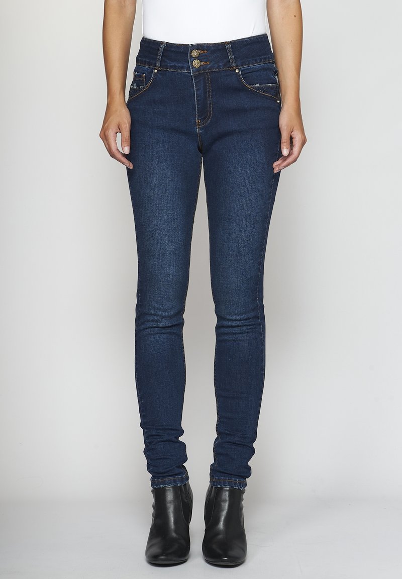 Mörkblå skinnjeans i denim med hög midja, med två framfickor med dekorationer och synliga sömnadsdetaljer.