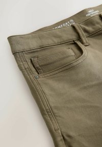 Olivově zelené bavlněné kalhoty s klasickým pětipocket designem, šitými detaily a malým kovovým knoflíkem na pase.
