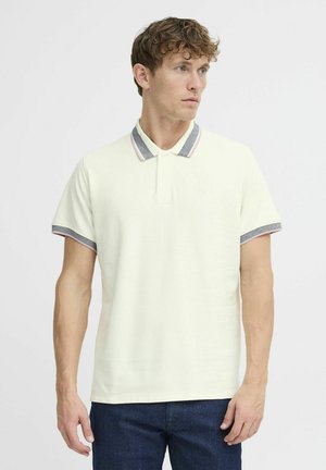 Short-sleeve polo shirt in cream with a ribbed collar and patterned accents in blue and pink. Cotton blend fabric with a relaxed fit.