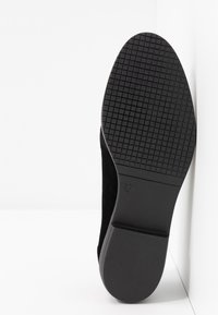 Semelle de chaussure noire avec un motif en grille sur la moitié avant et un talon lisse, taille marquée 37, sur fond blanc.