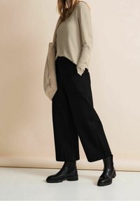 Beige long-sleeve sweater, black wide-leg trousers, and black ankle boots. Tote bag with a textured finish. Simple, modern outfit design.