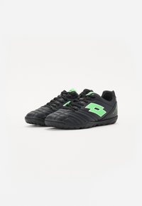 Black sports shoes with textured leather upper, lime green accents, lace closure, and a rugged outsole designed for traction.