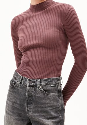 Eng anliegender gerippter Langarm-Rollkragenpullover in Mauve, kombiniert mit hoch taillierten gewaschenen schwarzen Denim-Jeans mit Fronttaschen und Knopfverschluss.