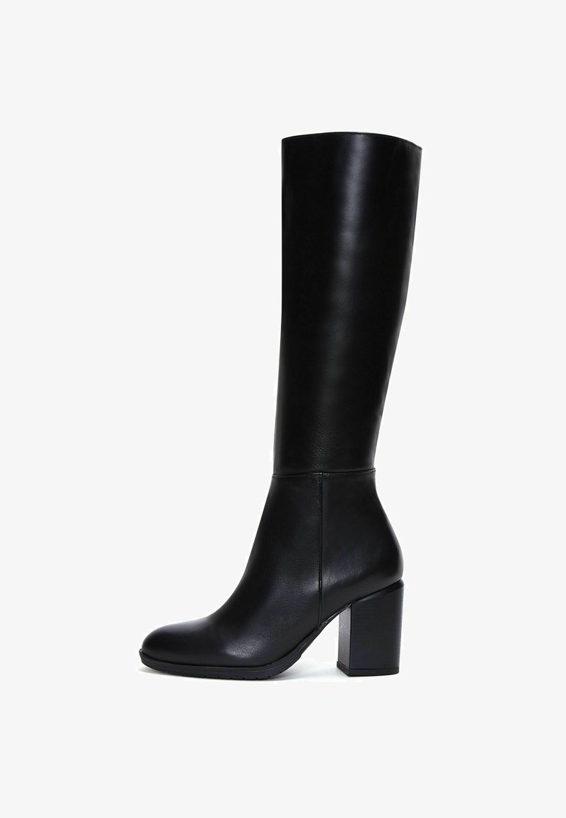 Botte en cuir noir montante, avec une texture lisse, un bout rond et un talon carré. Présente un minimum de matériel et un design épuré.
