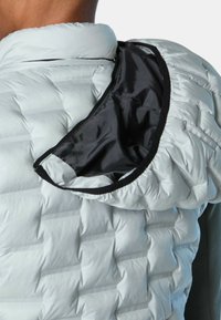 Hellgraue Steppjacke mit strukturiertem Quilt-Design, ausgestattet mit einem schwarzen Stofffutter und einem runden Kragen, teilweise geöffnet.