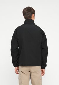Black jacket with a high collar and elastic cuffs. Features a simple design, lightweight material, and appears unlined on the back.