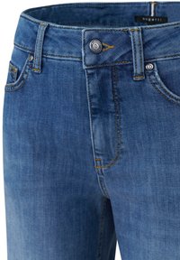 Dark blue denim jeans with a standard waistband, yellow stitching, front pockets, and a circular metal button featuring a brand logo.