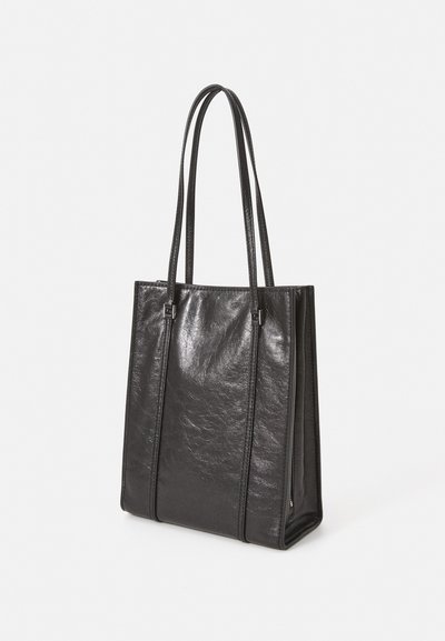 Borsa tote in pelle nera con texture liscia e cuciture verticali, dotata di due manici sottili e un ampio interno.