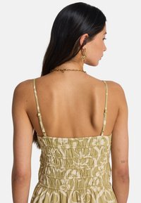 Πράσινο φόρεμα με σχέδιο, διαθέτει ρυθμιζόμενους λεπτούς ιμάντες, κορσέ με ραβδώσεις και ελαφρύ ύφασμα με λουλουδάτο σχέδιο.