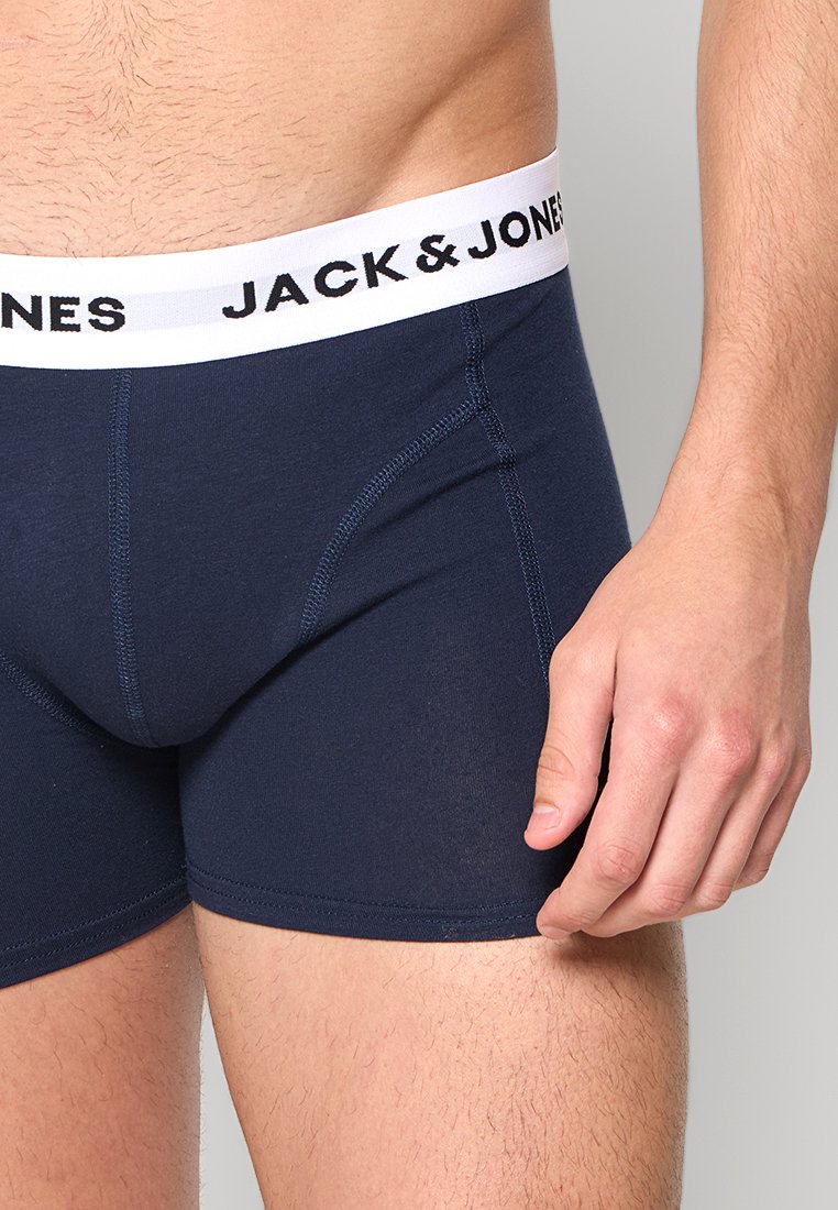 Primo piano di un uomo che indossa boxer blu navy con un elastico bianco etichettato "JACK & JONES" sul lato sinistro.