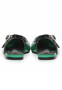 Sandalias de charol negras y verdes con parte trasera abierta, que cuentan con hebillas decorativas y una suela plana verde. Textura suave, diseño elegante.