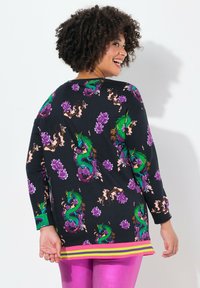 Maglietta nera a maniche lunghe con vivace stampa di drago e fiori, con orlo a righe gialle e rosa. Tessuto morbido con vestibilità rilassata.