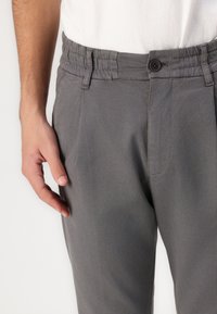 Gray trousers with a textured fabric, a button closure, and stitched waistband details. Pockets are integrated into the design.