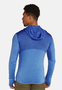 Maglietta con cappuccio a maniche lunghe in tonalità di blu sfumate, caratterizzata da un tessuto texturizzato, una silhoutte aderente e un design delle spalle senza cuciture.