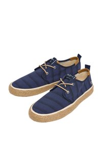 Scarpe in tela blu marino con righe orizzontali, suole in corda beige e dettagli marroni. Presentano un design con lacci e un logo sul tallone.