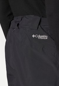 Črne tehnične hlače Columbia Titanium imajo teksturirano tkanino, prilagodljiv pas in vezeno logo na zadnjem žepu.