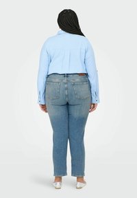 Hele sinine nööpidega särk, denim teksad, millel on kulunud viimistlus, viie taskuga disain ja kerge venitus. Hõbedased madalad kingad täiendavad riietust.